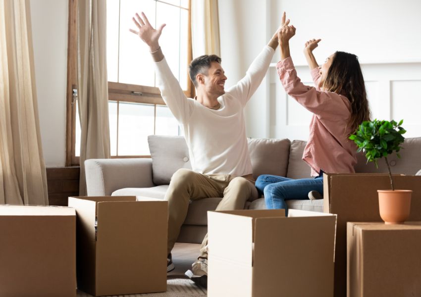 two-people-on-sofa-cheering-surrounded-by-boxes